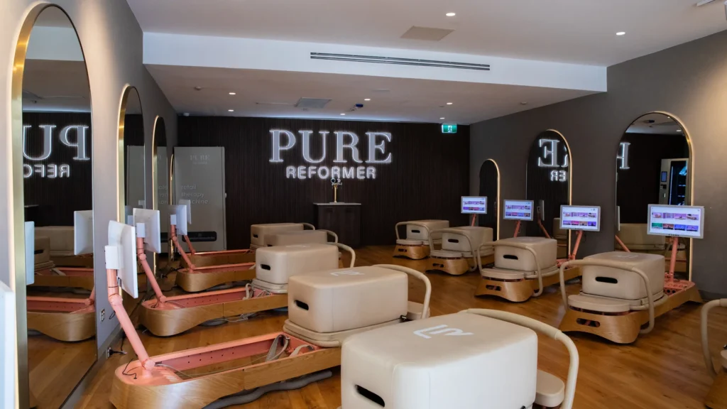 The Cronulla studio floor, reformers set beneath the lit wordmark